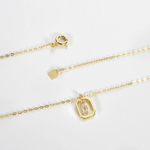 Detailed macro view of S925 sterling silver gold-plated D-letter pendant and hallmark tag