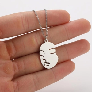 Detailed view of an abstract face line art pendant in silver stainless steel finish