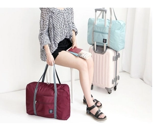 Close-up of waterproof foldable travel bags in wine red and light blue colors