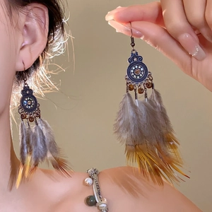 Detail of vintage bohemian flower drop earrings with brown feathers on a female model