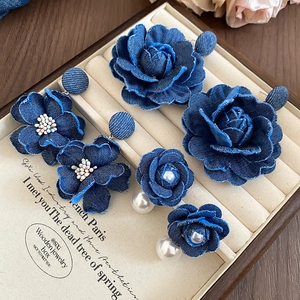 Detailed shot of denim fabric flower earrings with pearls in a wooden jewelry box