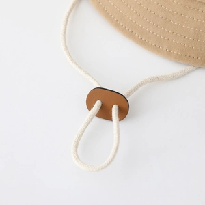 Detail of adjustable windproof rope with leather buckle on baby sun bucket hat