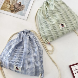 Dettaglio di zaini in tela con coulisse con quadretti verdi e blu e decori in perle