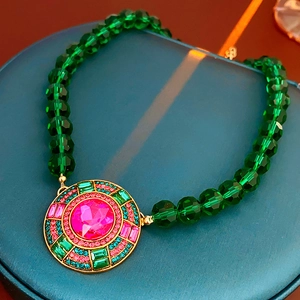 Dettaglio della collana vintage con perle smeraldo e ciondolo a fiore in gemma rosa