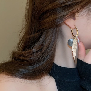 Detailed close-up of golden tassel earrings with sparkling rhinestones worn by a model