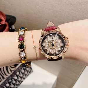 Detail of Dimini watch with rotating flower dial and leather strap worn with gemstone bracelet