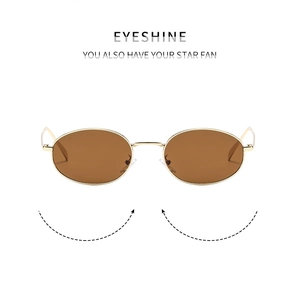 Close-up of retro oval sunglasses with slim gold metal frame and brown lenses