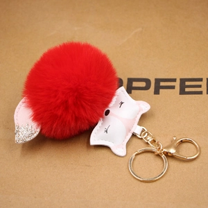 Detail of red plush fox keychain with leather fox head and gold lobster clasp charm