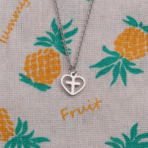 Detailed view of silver heart pendant with a cross on yellow patterned fabric
