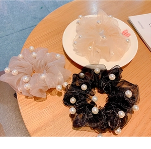 Detail of organza scrunchies in white, grey, and black colors with faux pearl accents