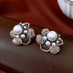 Close-up of vintage flower stud earrings with large white pearls and green rhinestones