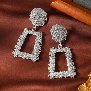 Silver geometric earrings with hammered texture on elegant dark silk background