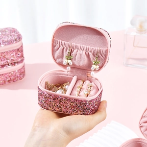 Pink glitter PU leather travel jewelry box with mirror and ring slots held in hand