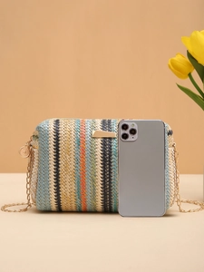 Detailed view of straw camera bag with gold chain strap beside a phone for size reference