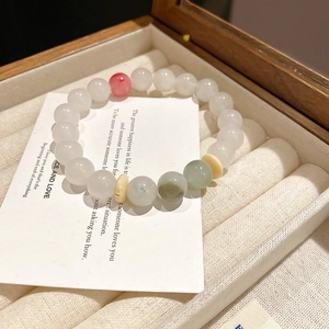Gros plan détaillé d'un bracelet en perles style jade blanc avec accents roses et verts