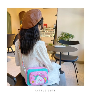 Rear view of a child wearing a unicorn crossbody bag with rainbow strap in a cafe setting