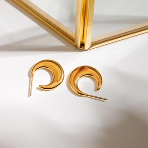 Macro view of gold C-shaped crescent earrings with smooth metallic polished finish