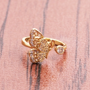 Vintage golden butterfly open ring with white zircons on a rustic wood background
