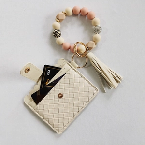 Detail of beige silicone beaded keychain bracelet with PU card wallet and tassel charm
