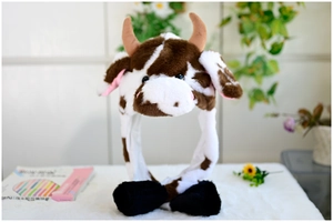 Detail showing plush cow hat with long ear flaps and cute black paw pattern mittens