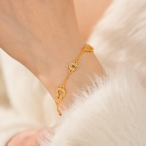 Detail of 24k gold plated bracelet with zircon gourd and coin charms on a wrist