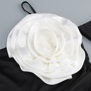 Macro view of a 3D white satin rose applique sewn on black fabric of a dress