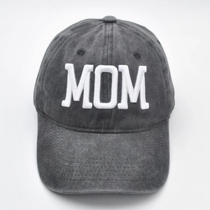 Macro detail of 3D embroidered white MOM text on a washed dark gray baseball cap