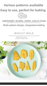 Detail view of Christmas tree and leaf shaped biscuit molds with pressed dough on a plate