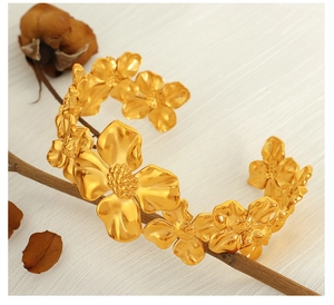 Macro detail of matte gold camellia open bangle with micro-carved floral texture