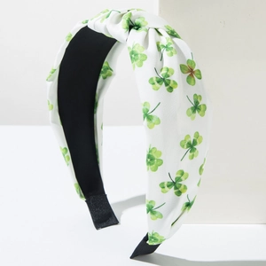 Close-up of knotted wide headband with green clover pattern on white fabric