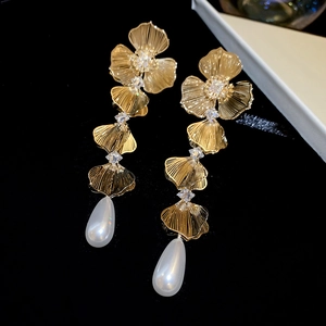 Detailed view of layered golden leaf earrings with crystals and teardrop pearl drops