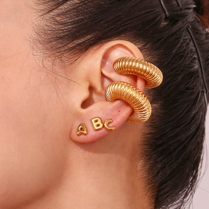 Detailed close-up of 18K gold-plated hollow threaded ear cuffs and letter stud earrings