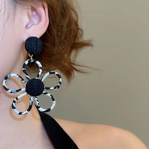 Détail de la boucle d'oreille fleur en tissu léopard avec centre tissé noir