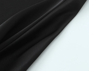 Close-up of black satin fabric texture with soft folds and high-end glossy finish
