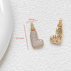 Detailed view of gold letter L pendant with cubic zirconia and back floral hollow design