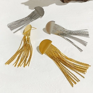 Gros plan de boucles d'oreilles à franges dorées et argentées sur un fond de pierre