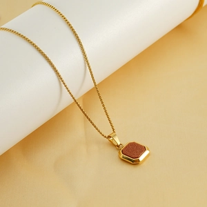 Détail macro du collier en acier inoxydable doré 18K avec pendentif carré marron brillant