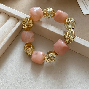 Detail of pink marble acrylic beads and irregular gold metal beads on a bracelet
