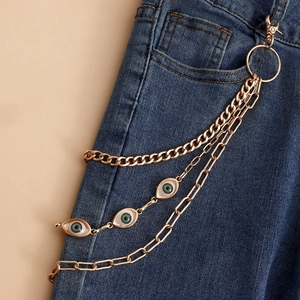 Close-up of gold layered hip-hop waist chain with green evil eye charms on denim jeans