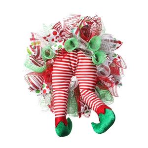 Détail d'une couronne de Noël avec jambes de lutin rayées et chaussures en velours vert déco