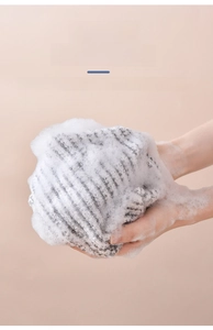 Close-up of dual-tone gray and white loofah sponge producing rich and dense foam