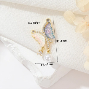 Macro detail of 14k gold butterfly pendant with enamel wings, zircon, and pearl drop