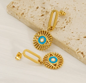 Macro view of gold-plated evil eye earrings with blue enamel on natural stone