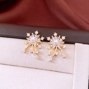 Vue détaillée des boucles d'oreilles flocon avec perles et zircons sur boîte en velours
