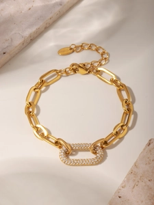 Detail of gold chain bracelet featuring a zircon-encrusted oval clasp on marble