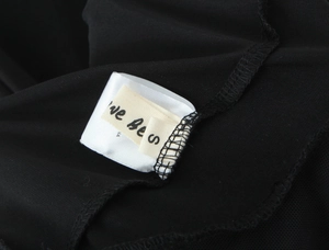 Close-up of size S label and stitching detail on a black chiffon sleeveless dress