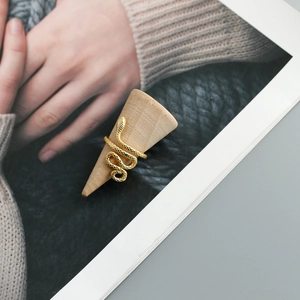 Detailed view of a gold snake-shaped fashion ring displayed on a wooden cone stand