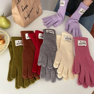 Flat lay of colorful knitted winter gloves in purple, green, and pink on a table