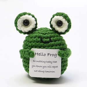 Detail of hand-knitted green frog holding an inspirational card on a white background