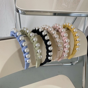 Detail of colorful fabric headbands with large white pearls on a minimalist chair